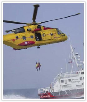 Helicopter lowering trained Search and Rescue personnel to Coast Guard Ship